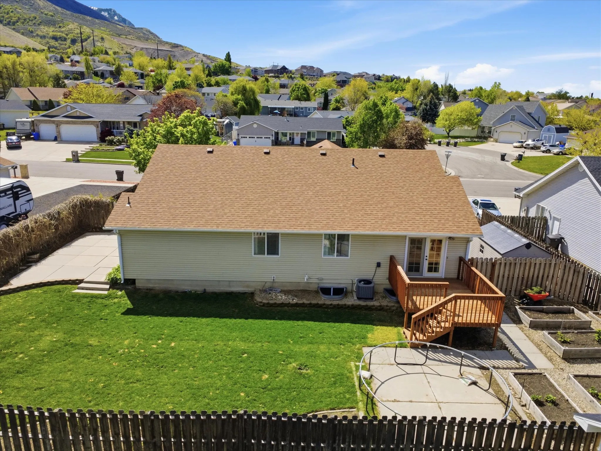 Rear view of property with a fenced backyard, a deck with mountain view, and a vegetable garden