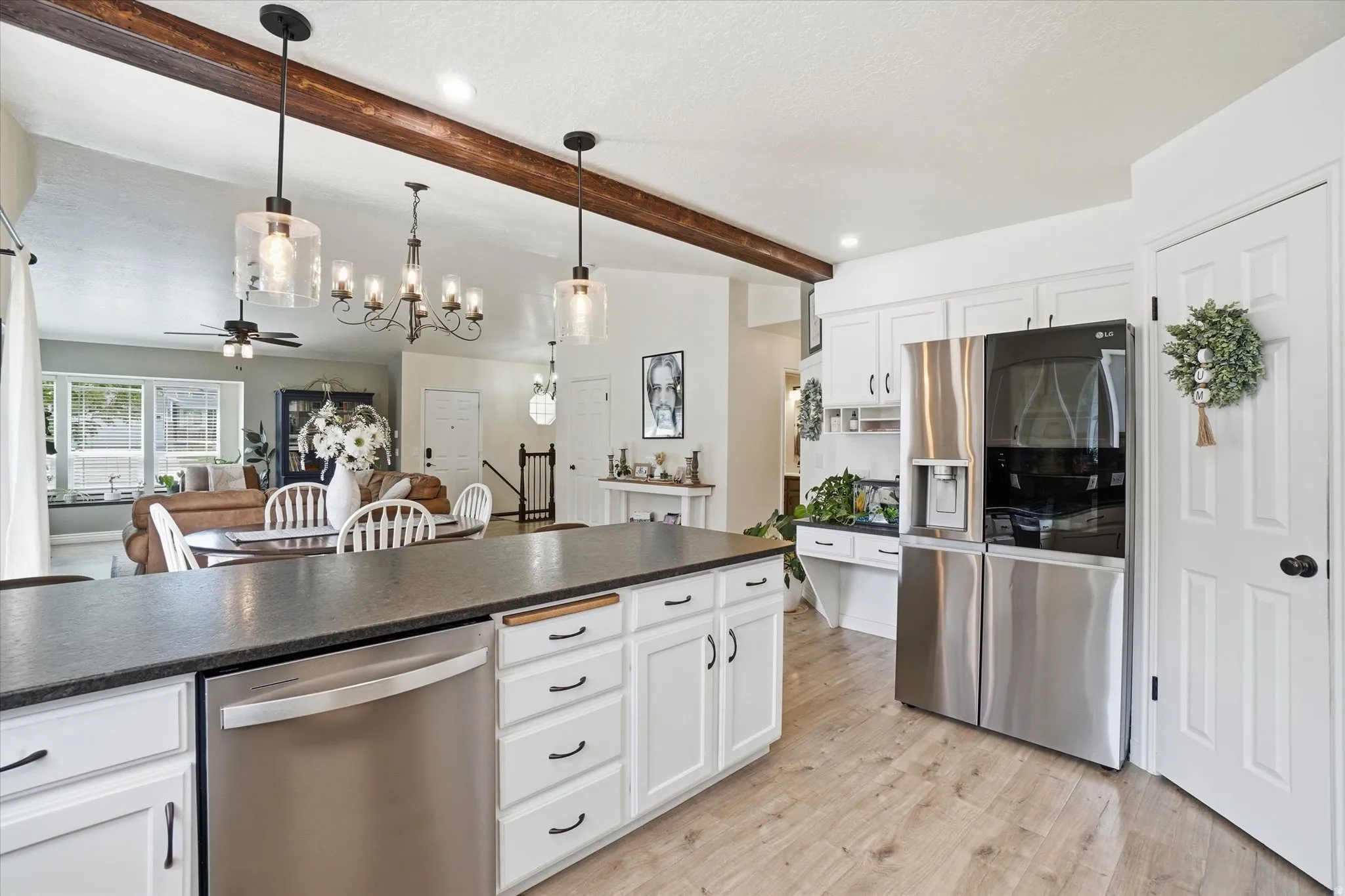 Kitchen featuring stainless steel appliances, white cabinets, dark countertops, open floor plan, and LVP floors