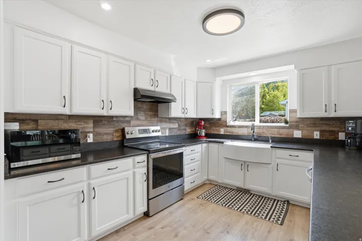Kitchen with stainless steel appliances, white cabinets, LVP floors, recessed lighting, and leather granite countertops
