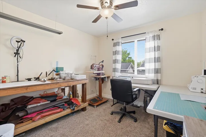 Office area with a ceiling fan and light carpet