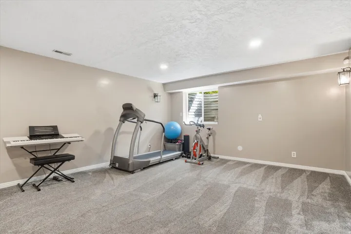 Exercise area featuring a textured ceiling, light carpet, and recessed lighting