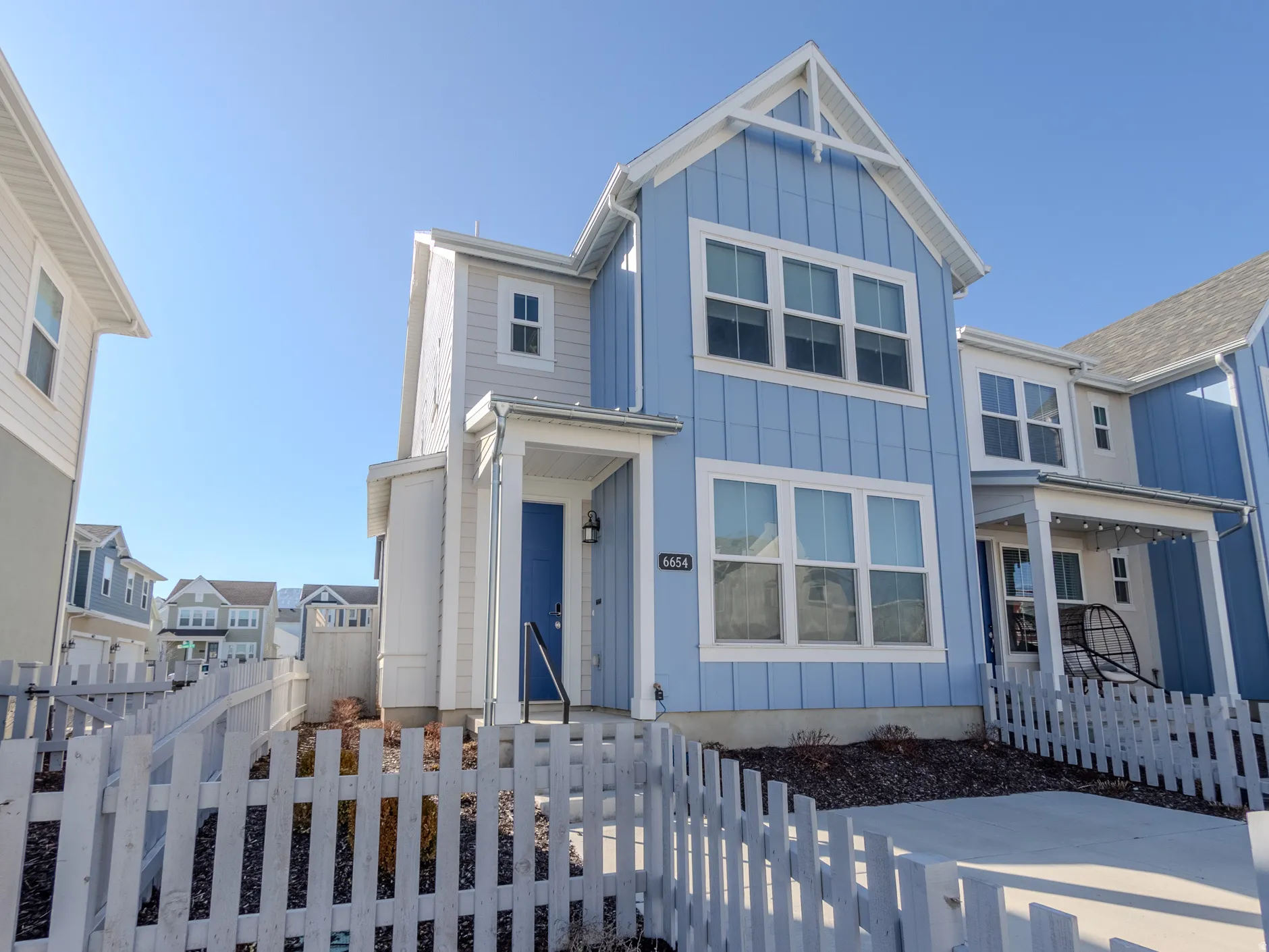 View of front of home with board and batten siding, a fenced front yard, and a gate