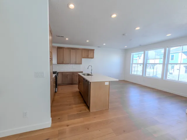 Kitchen with a center island with sink, light wood-type flooring, recessed lighting, tasteful backsplash, and range with gas stovetop