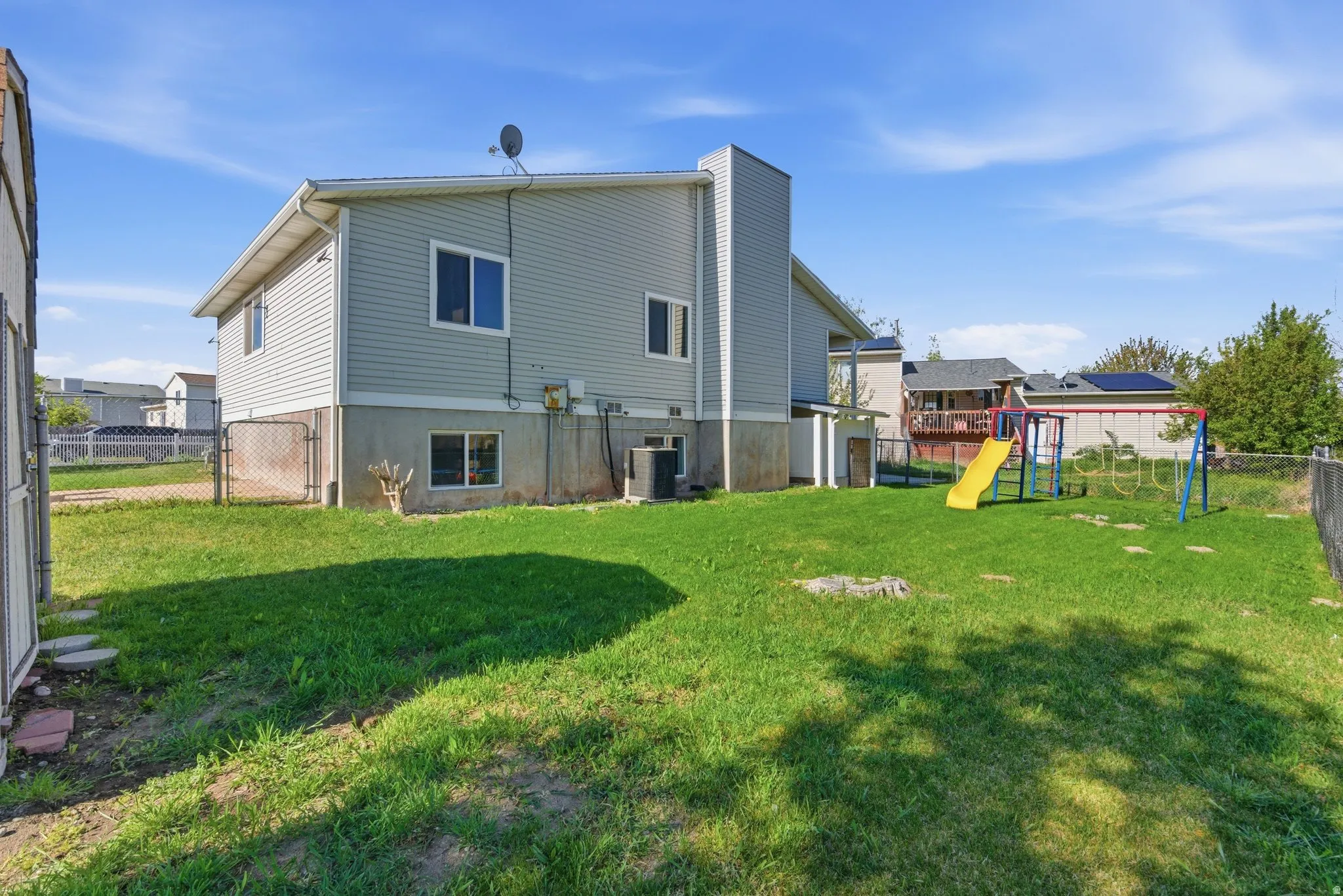 Rear view of property with a fenced backyard, a playground, and a gate