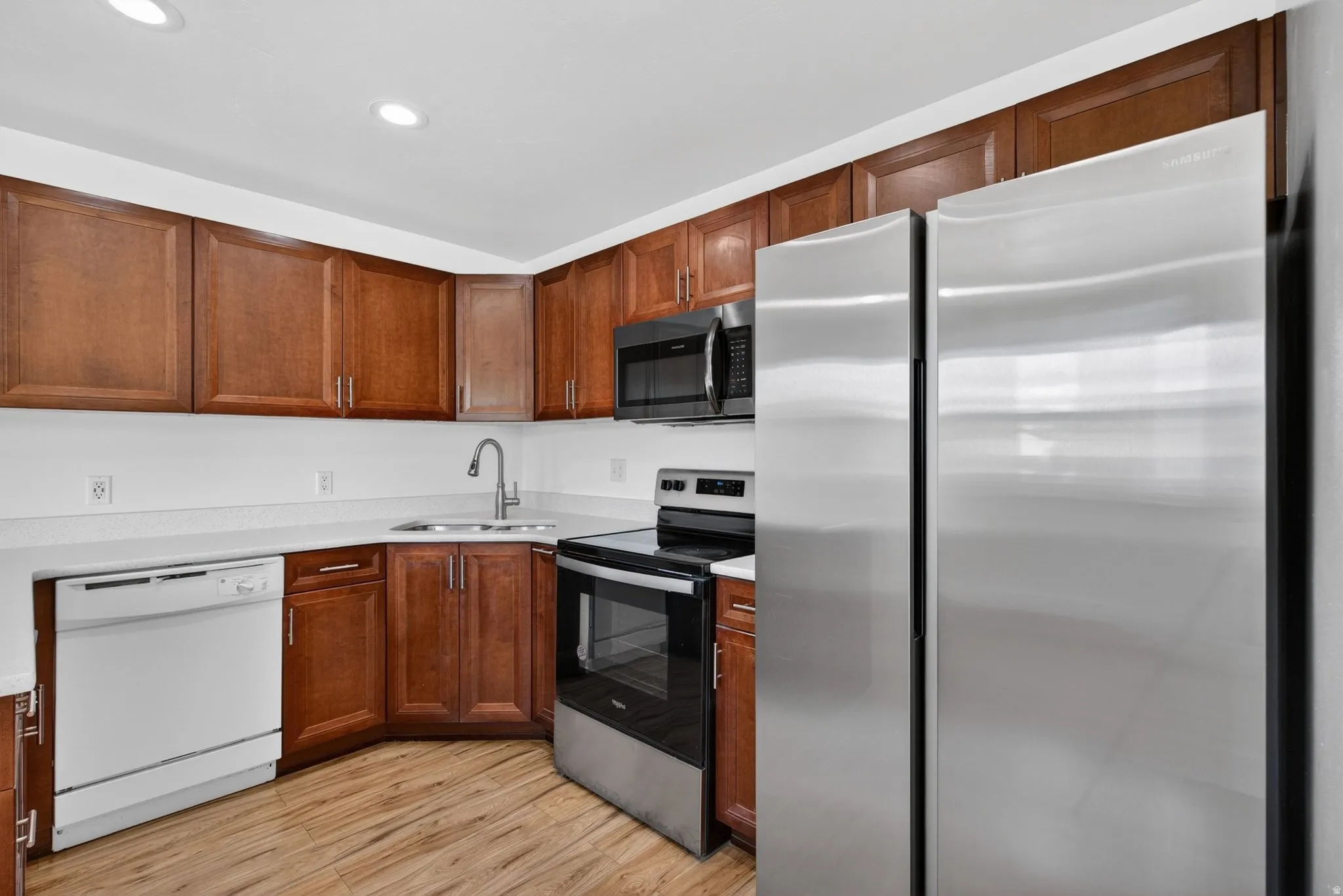 Kitchen with stainless steel appliances, light wood-style floors, wood finish cabinets, and recessed lighting