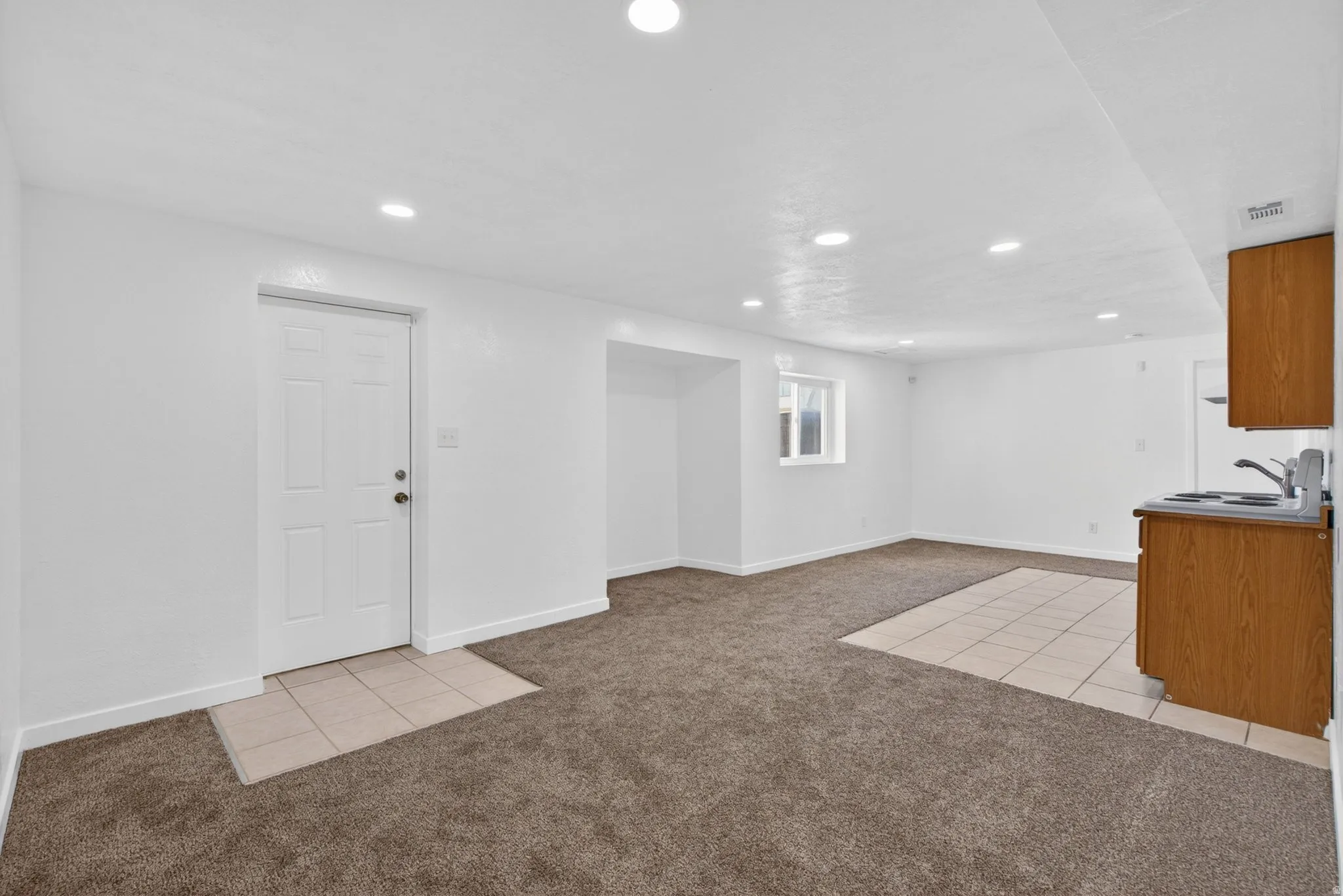 Below grade area with light tile patterned flooring, light colored carpet, and recessed lighting