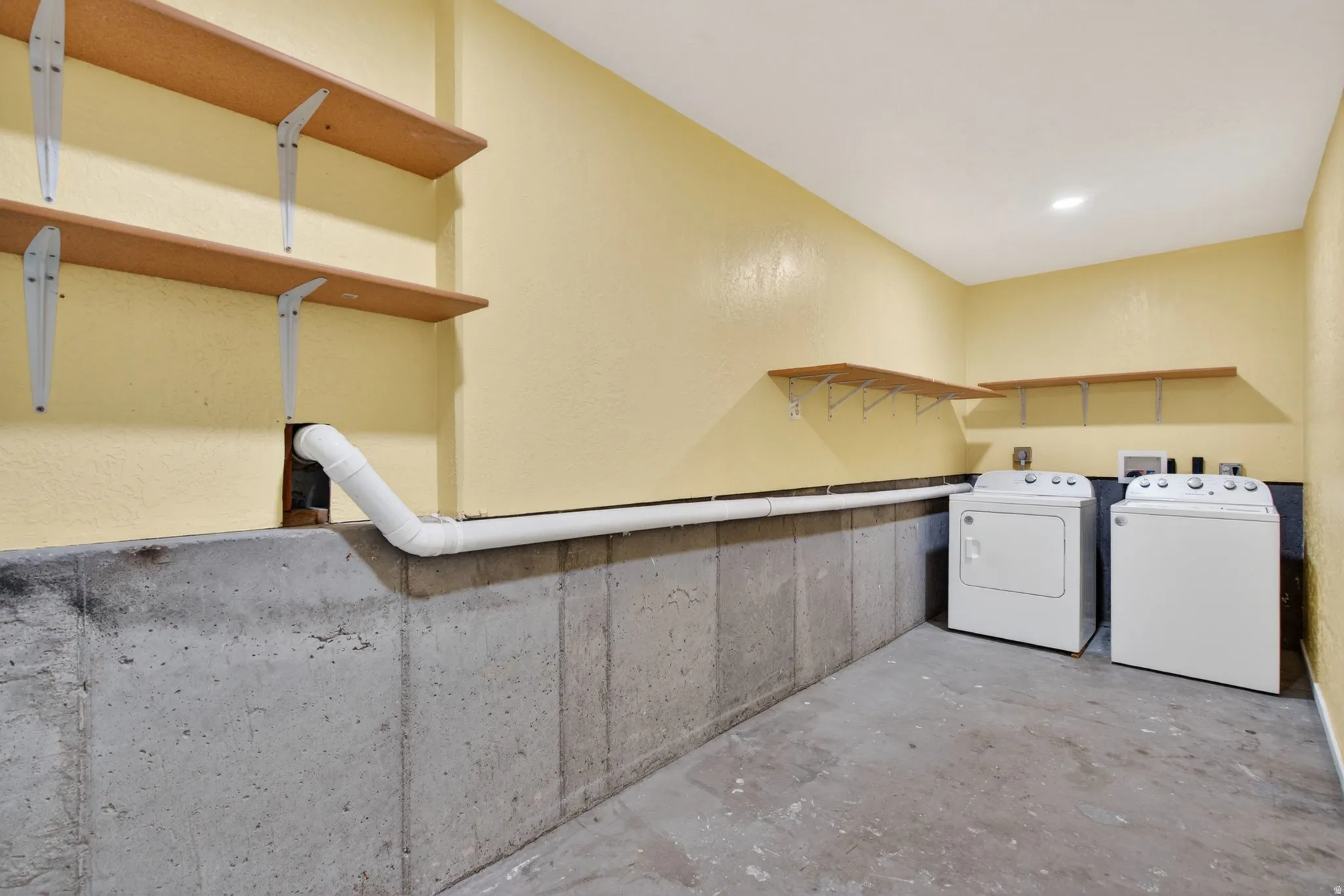 Laundry area with unfinished concrete flooring and independent washer and dryer