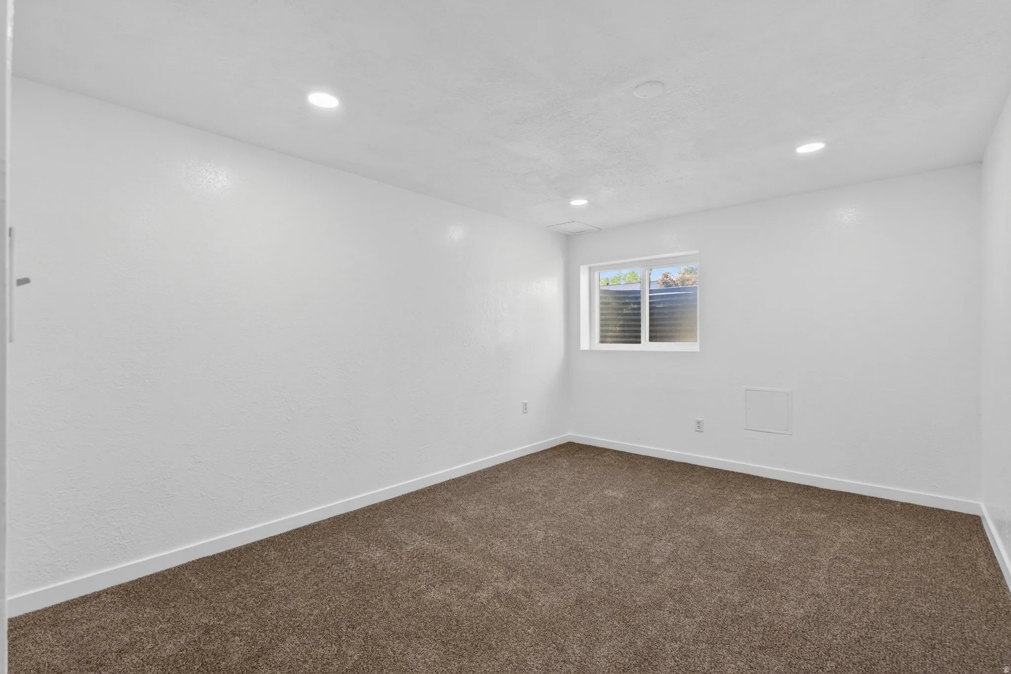 Empty room featuring dark colored carpet and recessed lighting