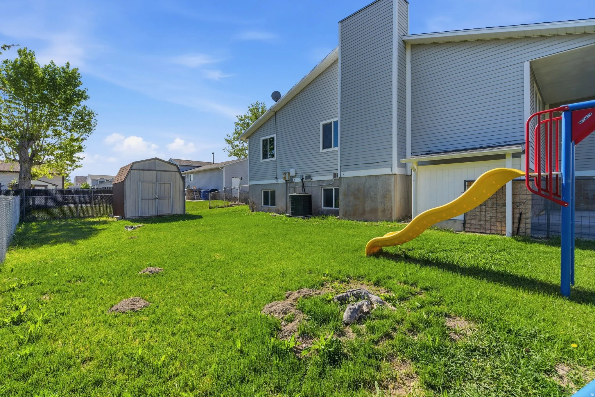 Fenced backyard with a storage shed and a playground