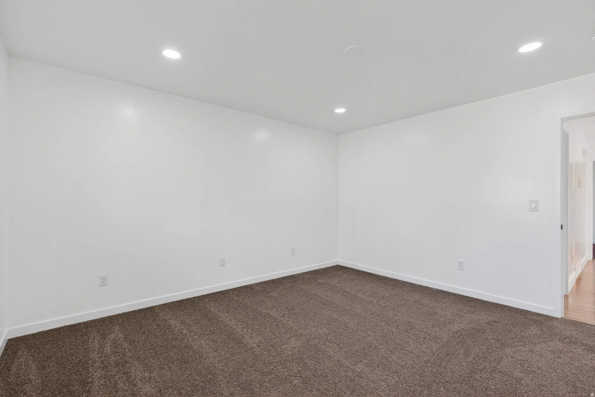 Unfurnished room with dark colored carpet and recessed lighting