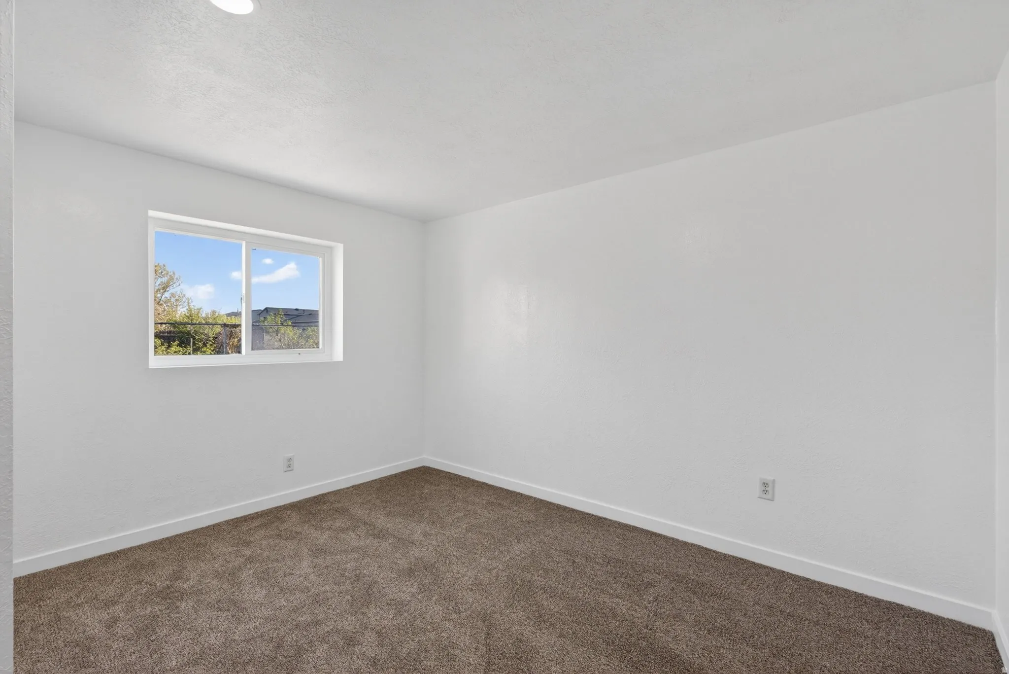 Unfurnished room with baseboards and dark carpet