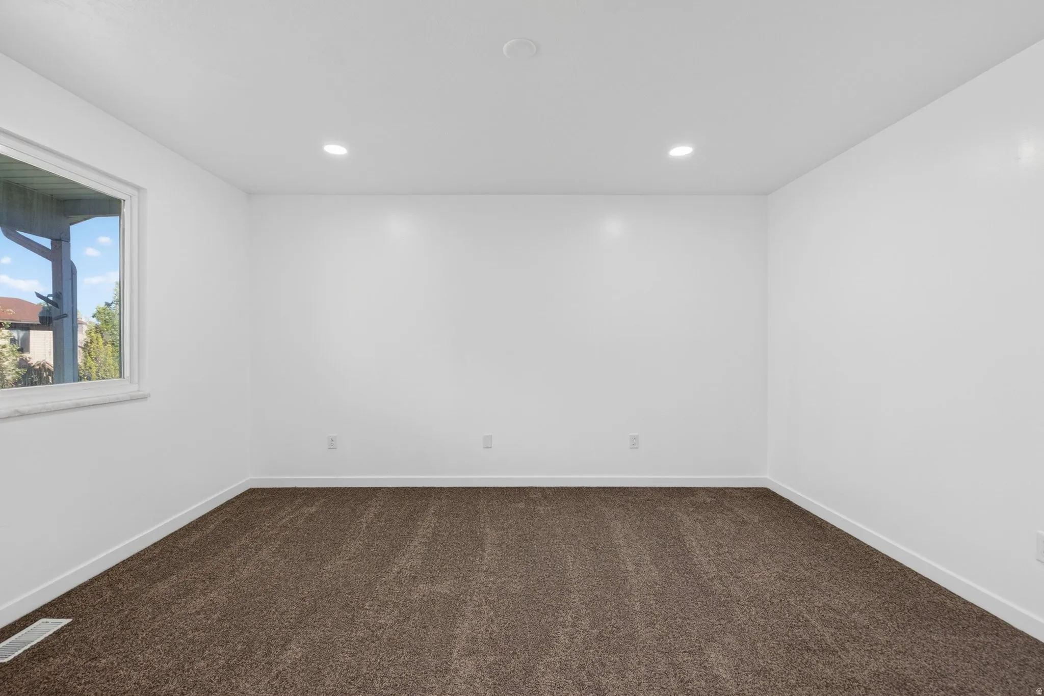 Empty room with dark carpet and recessed lighting