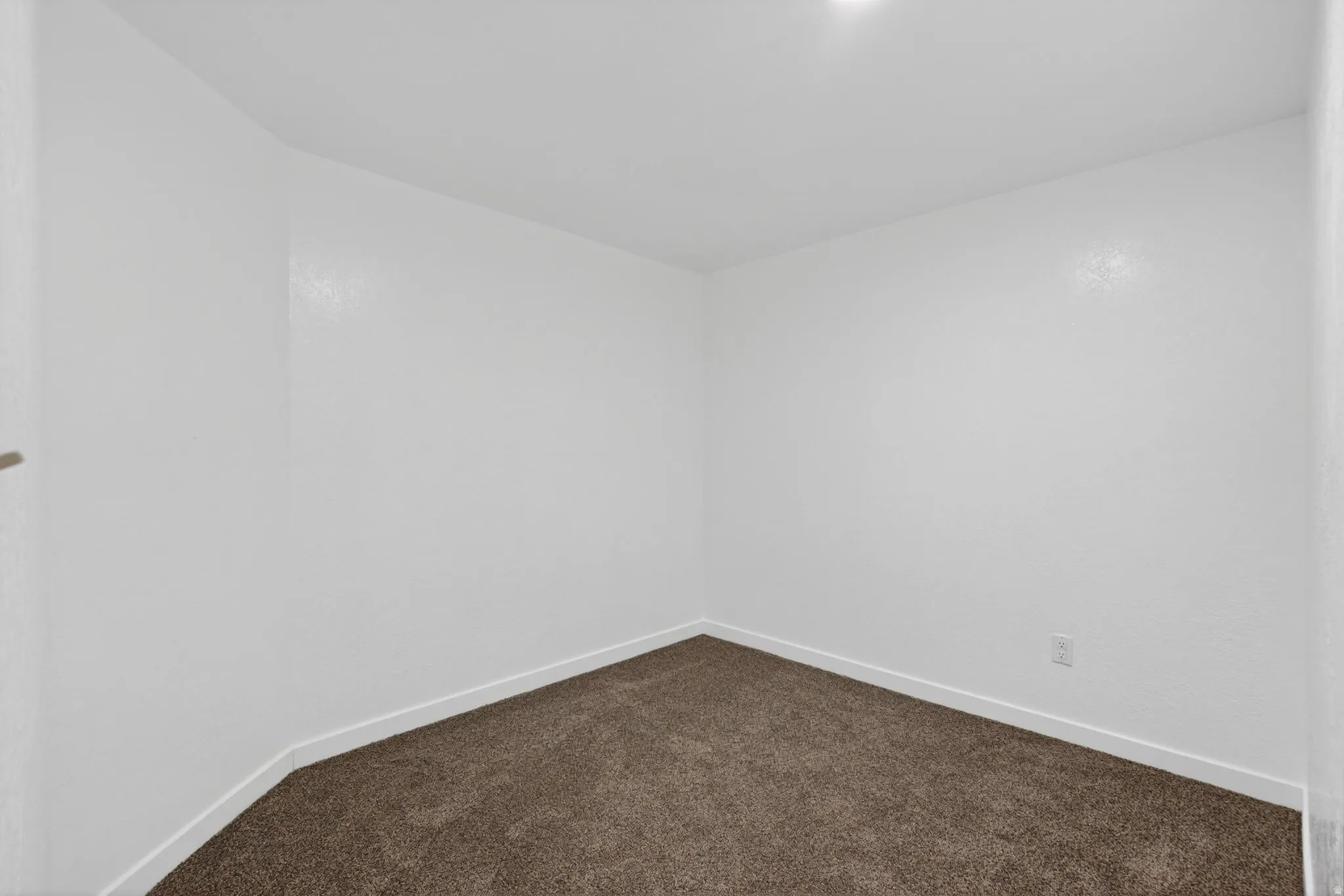 Empty room with baseboards and dark colored carpet