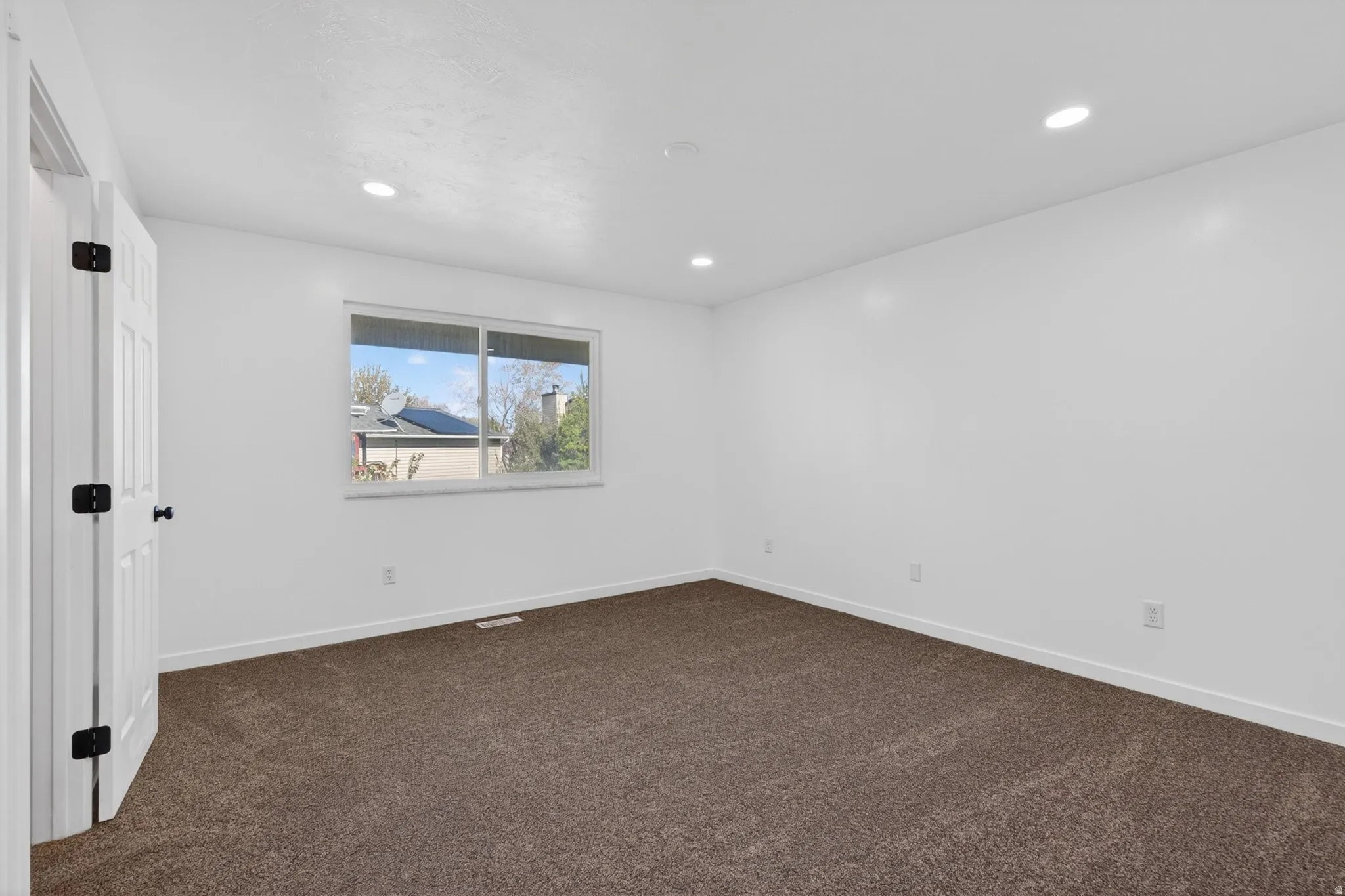 Empty room with dark carpet and recessed lighting