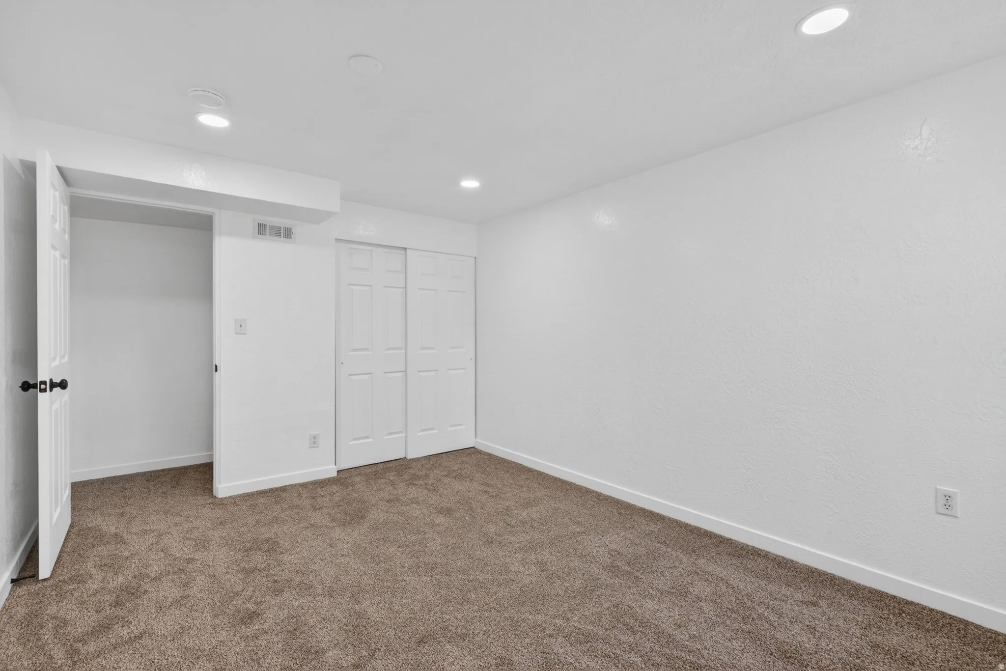Unfurnished bedroom with a closet, dark colored carpet, and recessed lighting