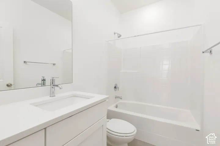 White vanity with an integrated sink, polished chrome faucet, full-width mirror, and a white tub with a shower surround