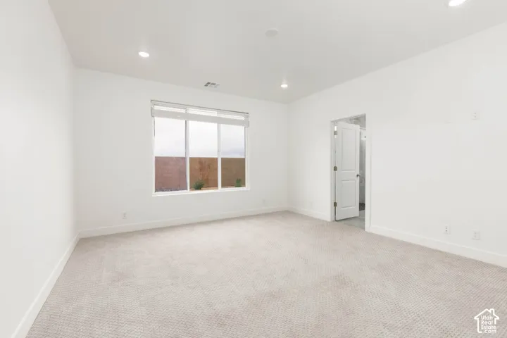 Spacious room with plush carpet flooring, recessed lighting, and a large window with roller shades