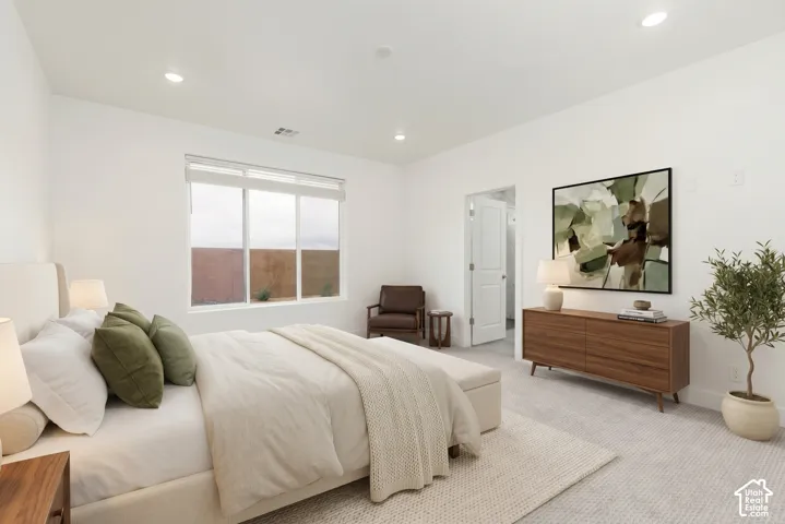 Recessed lighting, large window with roller shades, light-colored carpeting, white walls, and white interior door