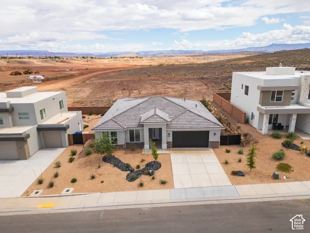Contemporary exterior with a tiled roof, attached two-car garage, and desert-style landscaping