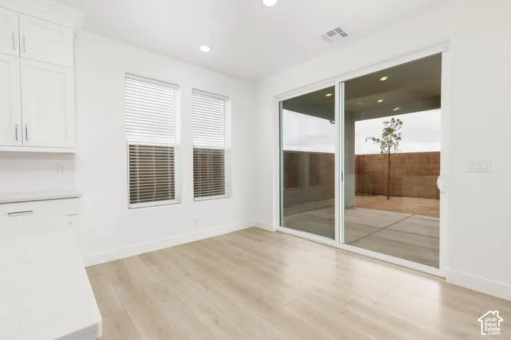 Wood-finish flooring, white cabinetry with silver hardware, and white countertops