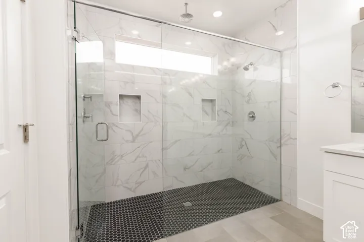 Expansive walk-in shower with clear glass enclosure and black hexagonal tile flooring