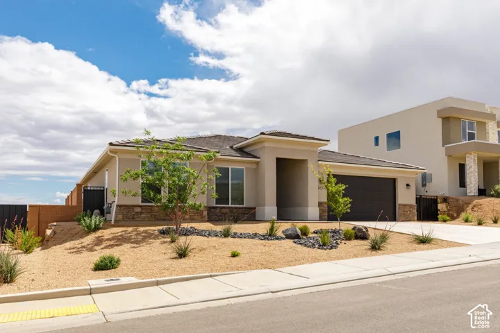 Contemporary stucco exterior with a stone veneer accent, attached two-car garage, and desert-style landscaping