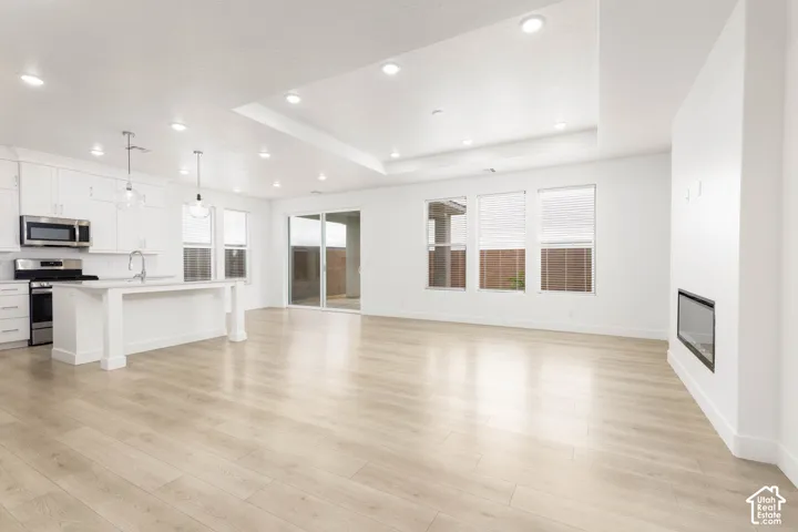 Open-concept living area with wood-finish flooring, recessed lighting, and a modern linear fireplace