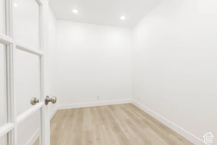 French doors with glass panels, wood-finish flooring, recessed lighting, and bright white walls