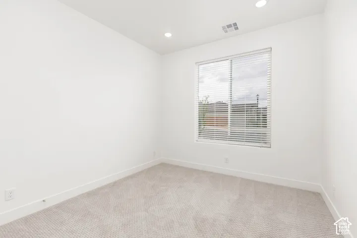 Recessed lighting, large window with blinds, carpeted flooring, and white walls