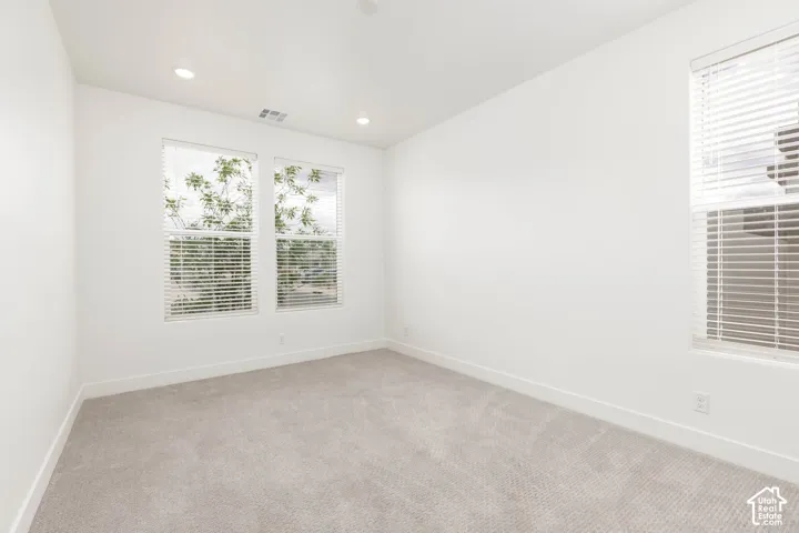 Recessed lighting, textured carpeting, multiple windows with blinds, and neutral wall finishes