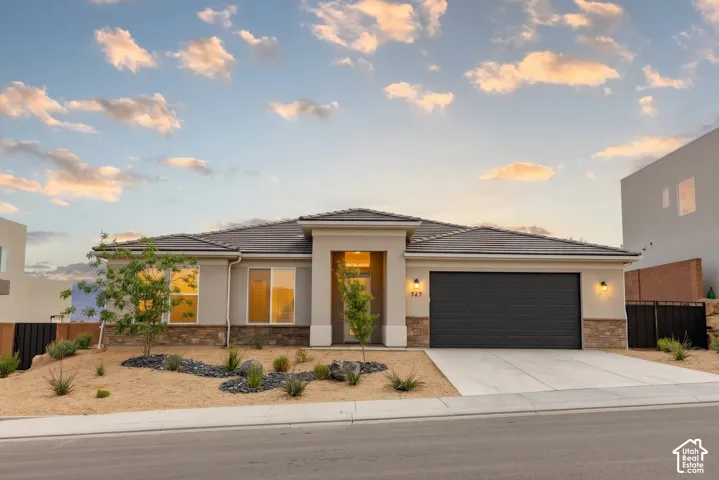 Exterior Front: A single-level 2024 build with stacked-stone accents, a concrete tile roof, a 2-car garage, and low-water desert landscaping out front.