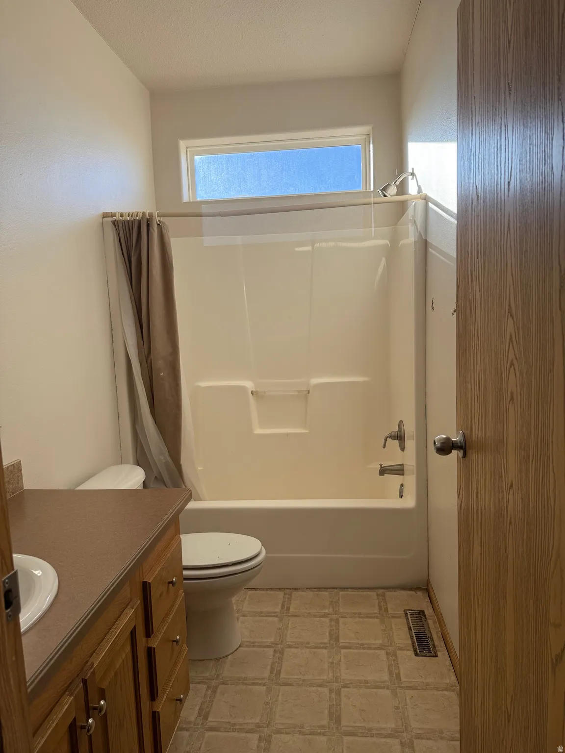 Bathroom featuring vanity, shower / bath combo with shower curtain, light flooring, and a textured ceiling