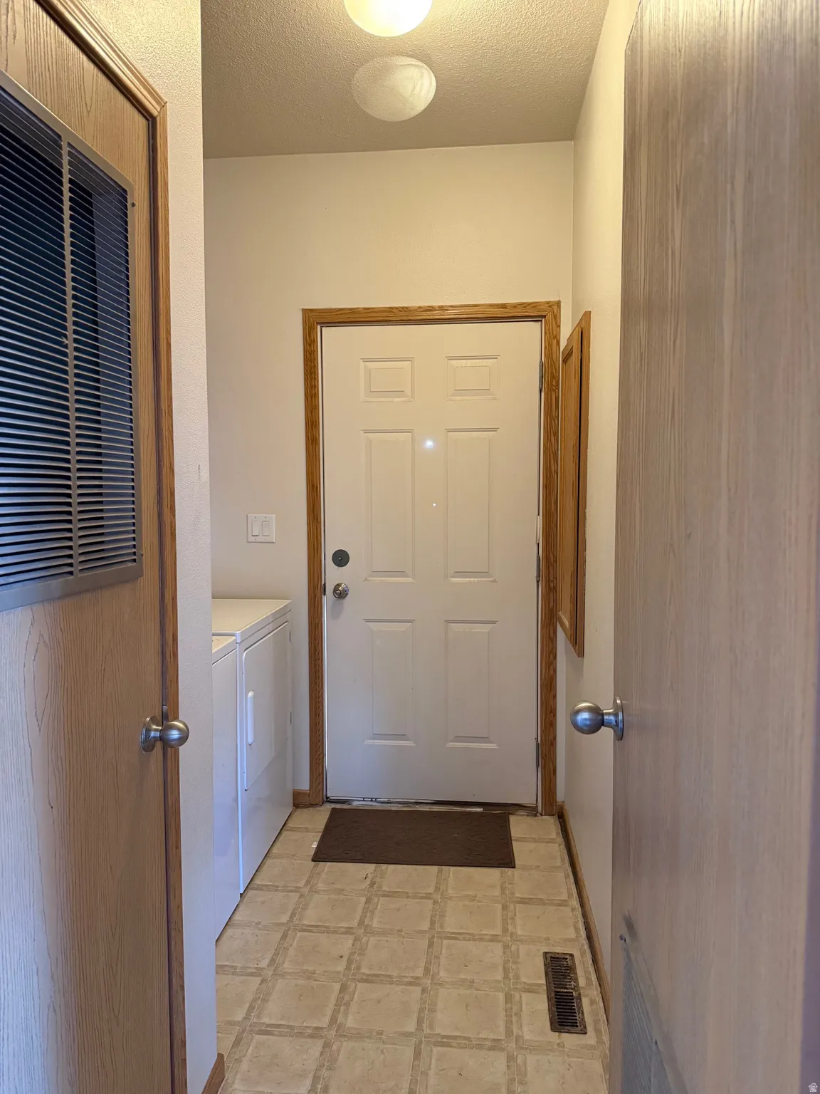 Laundry room with light floors, a heating unit, a textured ceiling, and separate washer and dryer