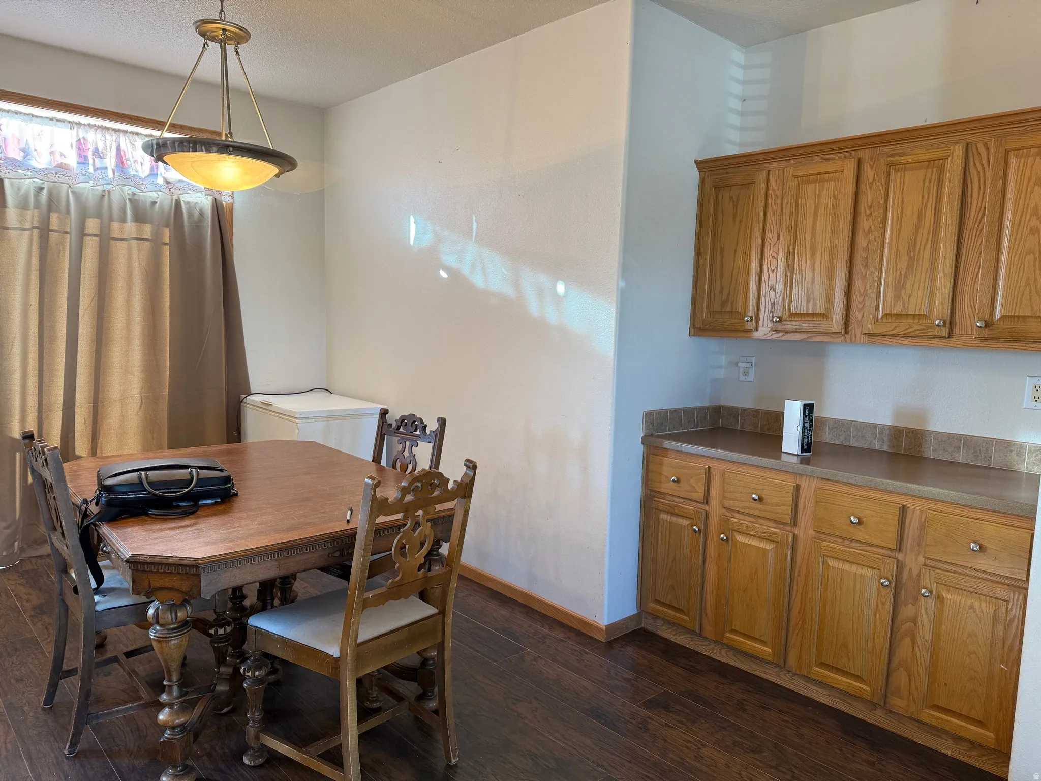 Dining space with dark wood-style flooring and baseboards