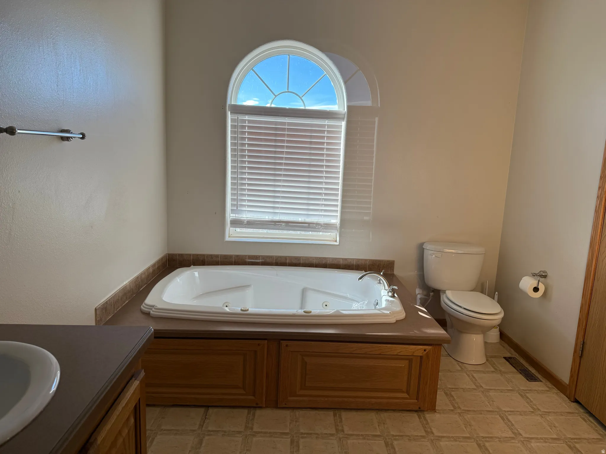 Full bath featuring a whirlpool tub, vanity, and light floors