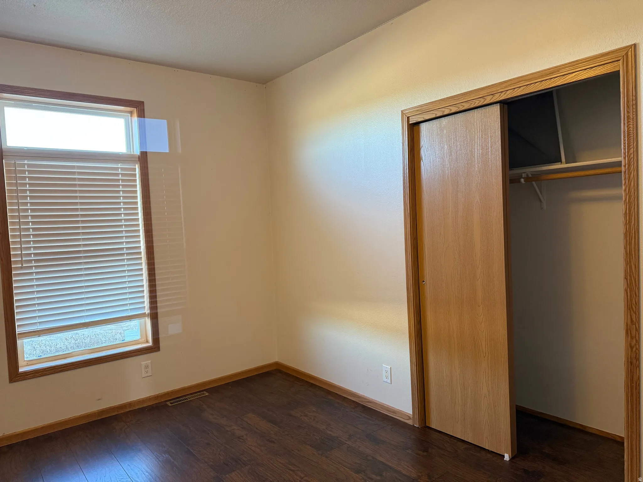 Unfurnished bedroom featuring dark wood-style floors and a closet