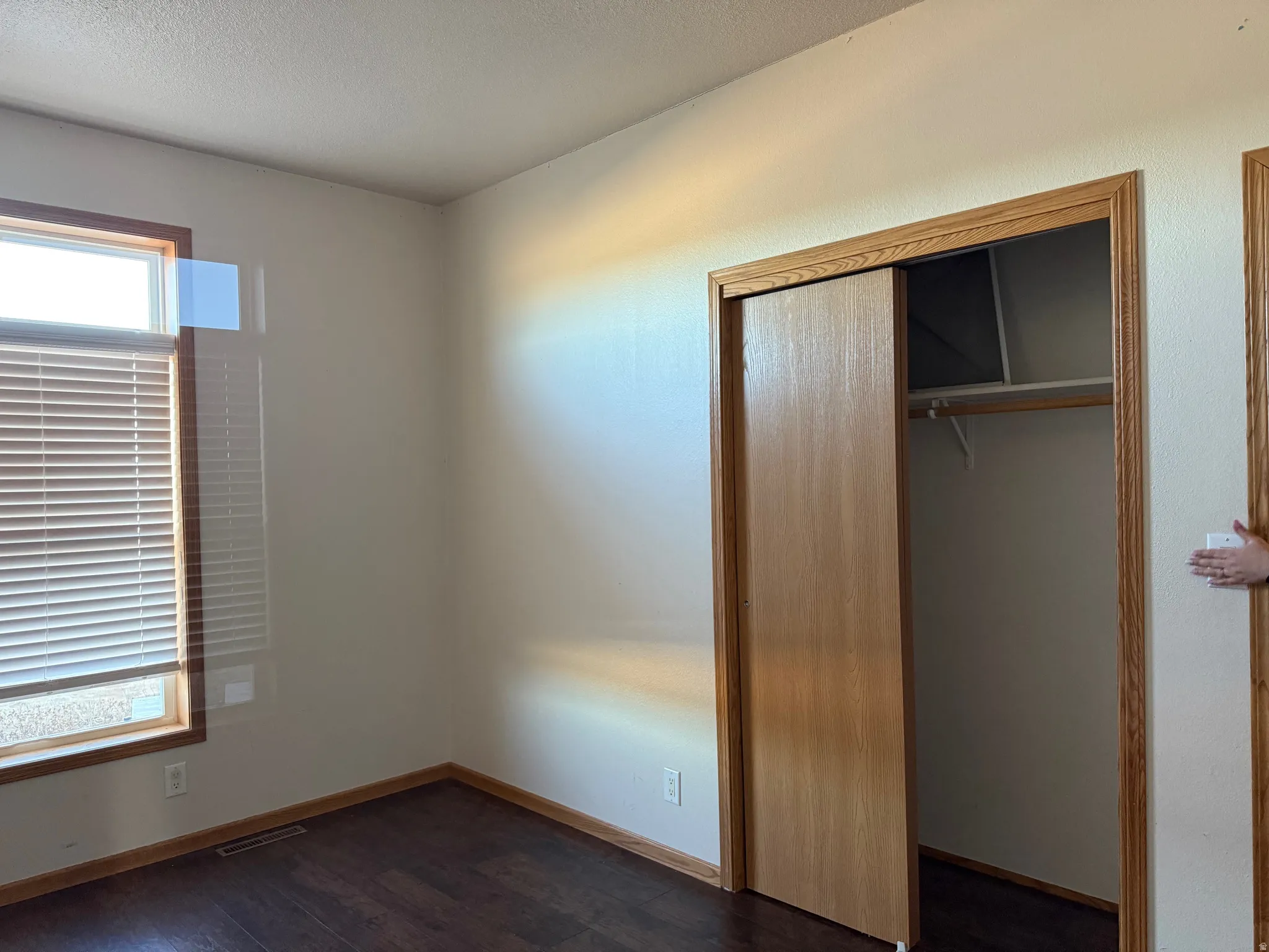 Unfurnished bedroom featuring a closet, dark wood-style flooring, and a textured ceiling