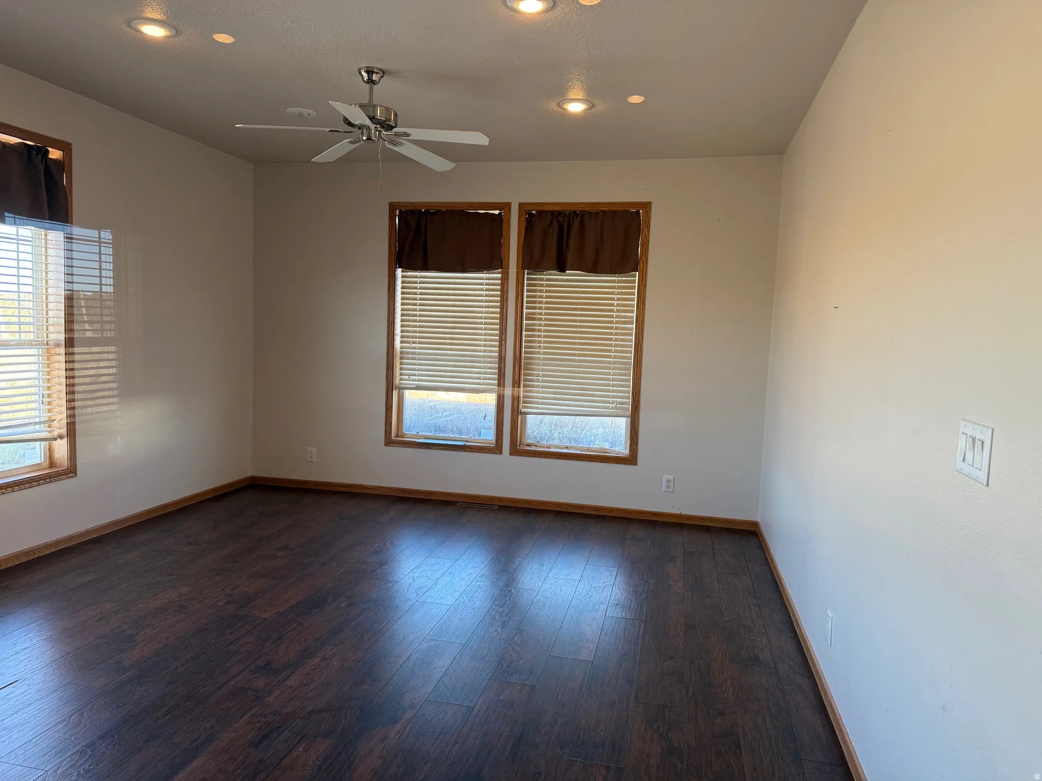 Unfurnished room featuring ceiling fan, healthy amount of natural light, recessed lighting, and dark wood-style flooring