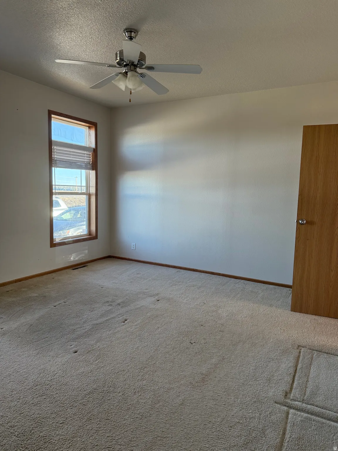 Spare room with a textured ceiling, light carpet, and ceiling fan