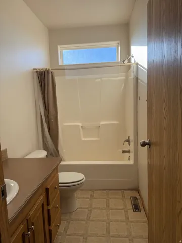 Bathroom featuring vanity, shower / bath combo with shower curtain, light flooring, and a textured ceiling