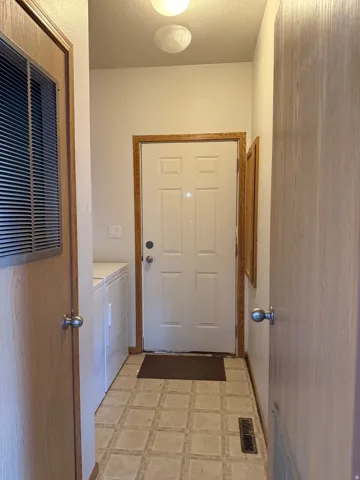 Laundry room with light floors, a heating unit, a textured ceiling, and separate washer and dryer