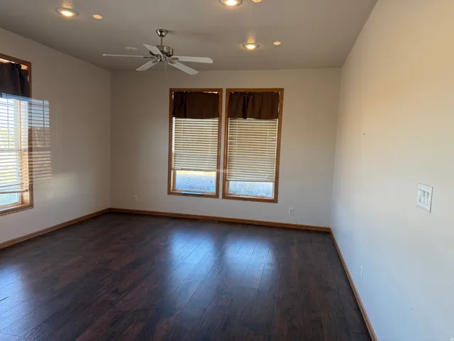 Unfurnished room featuring ceiling fan, healthy amount of natural light, recessed lighting, and dark wood-style flooring