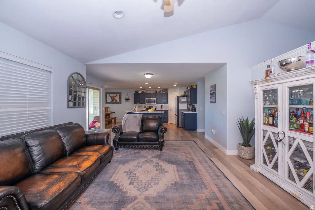 Living room featuring vaulted ceiling, light wood-type flooring, a ceiling fan, and recessed lighting