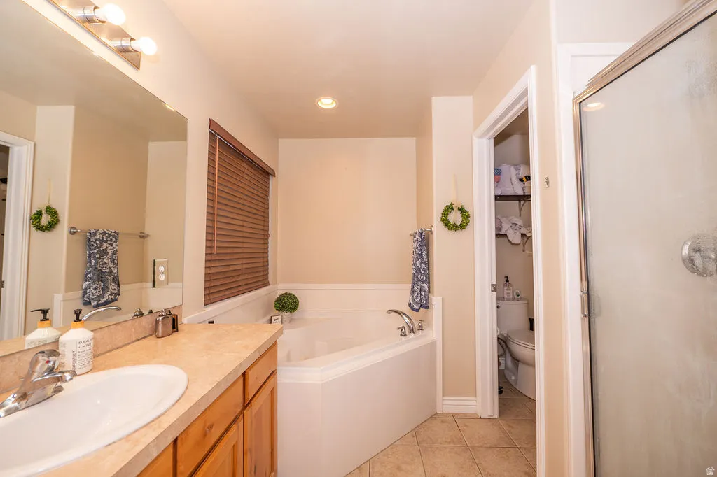 Bathroom featuring vanity, light tile patterned flooring, a bath, a shower stall, and recessed lighting