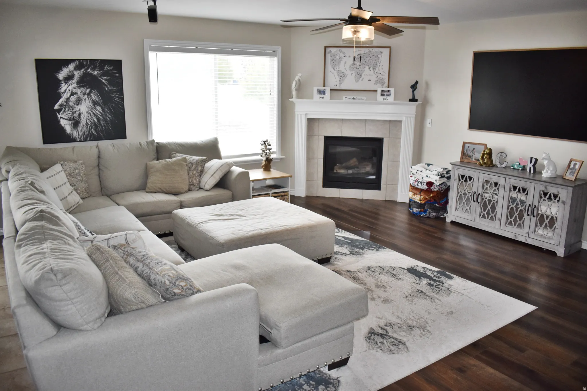 Living room with dark wood-type flooring, ceiling fan, and a tile fireplace