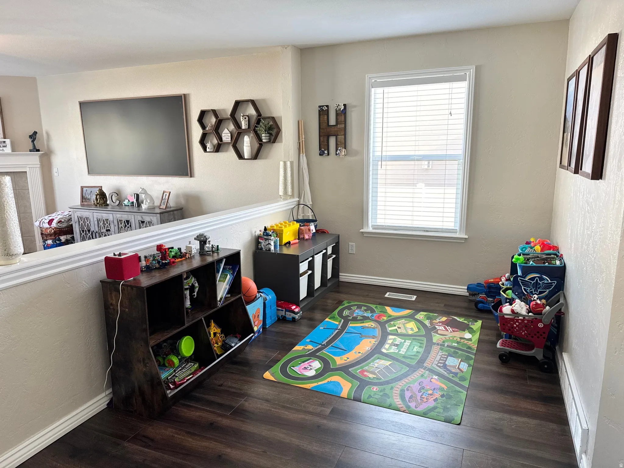 Rec room featuring a textured wall and dark wood-style floors