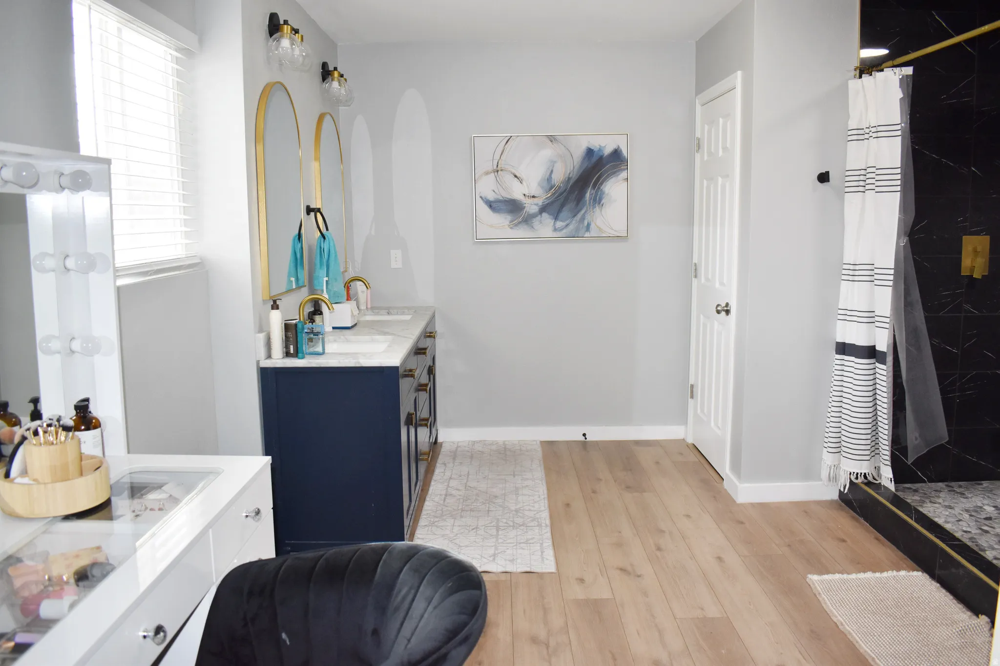 Full bathroom with double vanity, light wood finished floors, and a shower stall