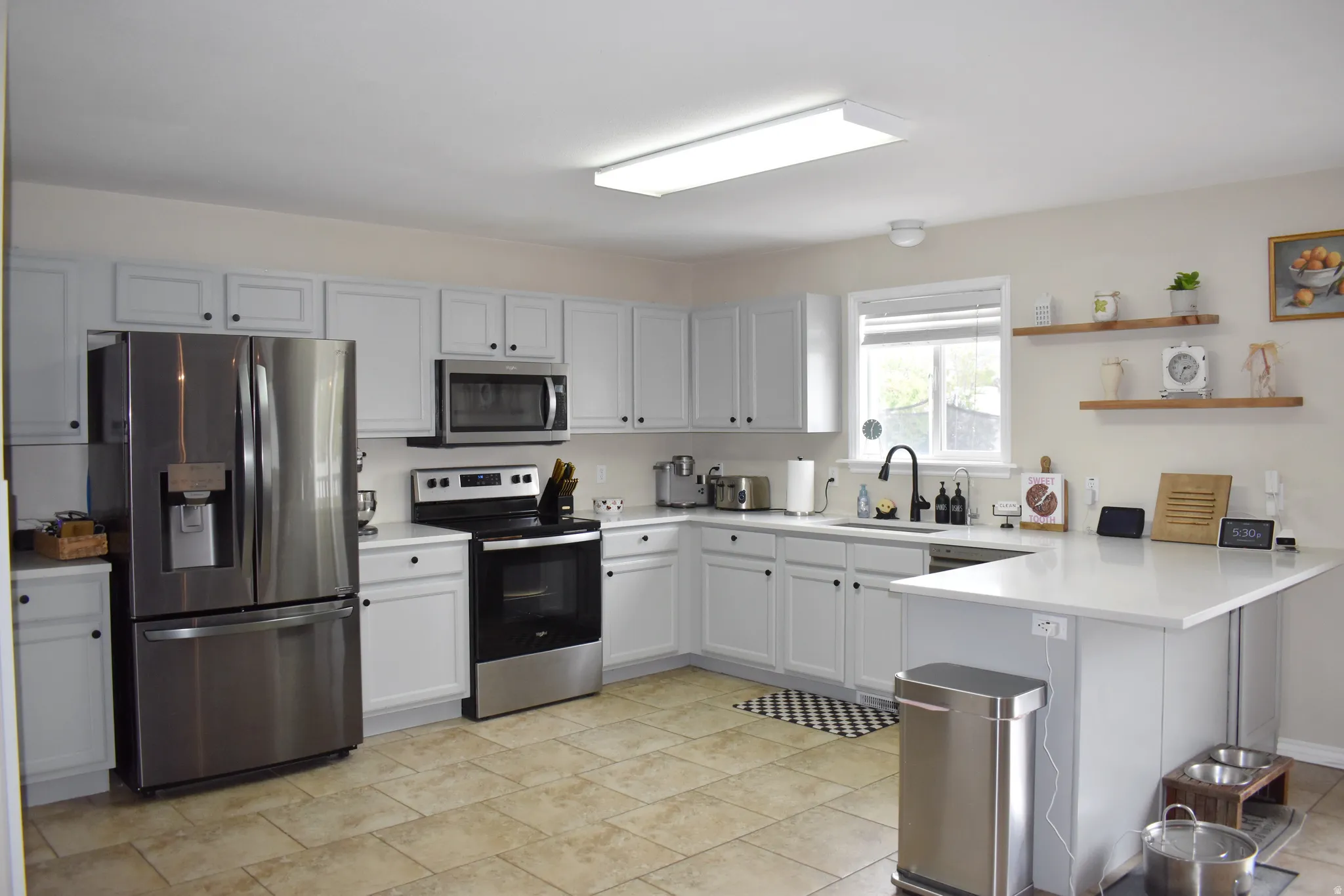 Kitchen with a peninsula, stainless steel appliances, open shelves, and a breakfast bar area