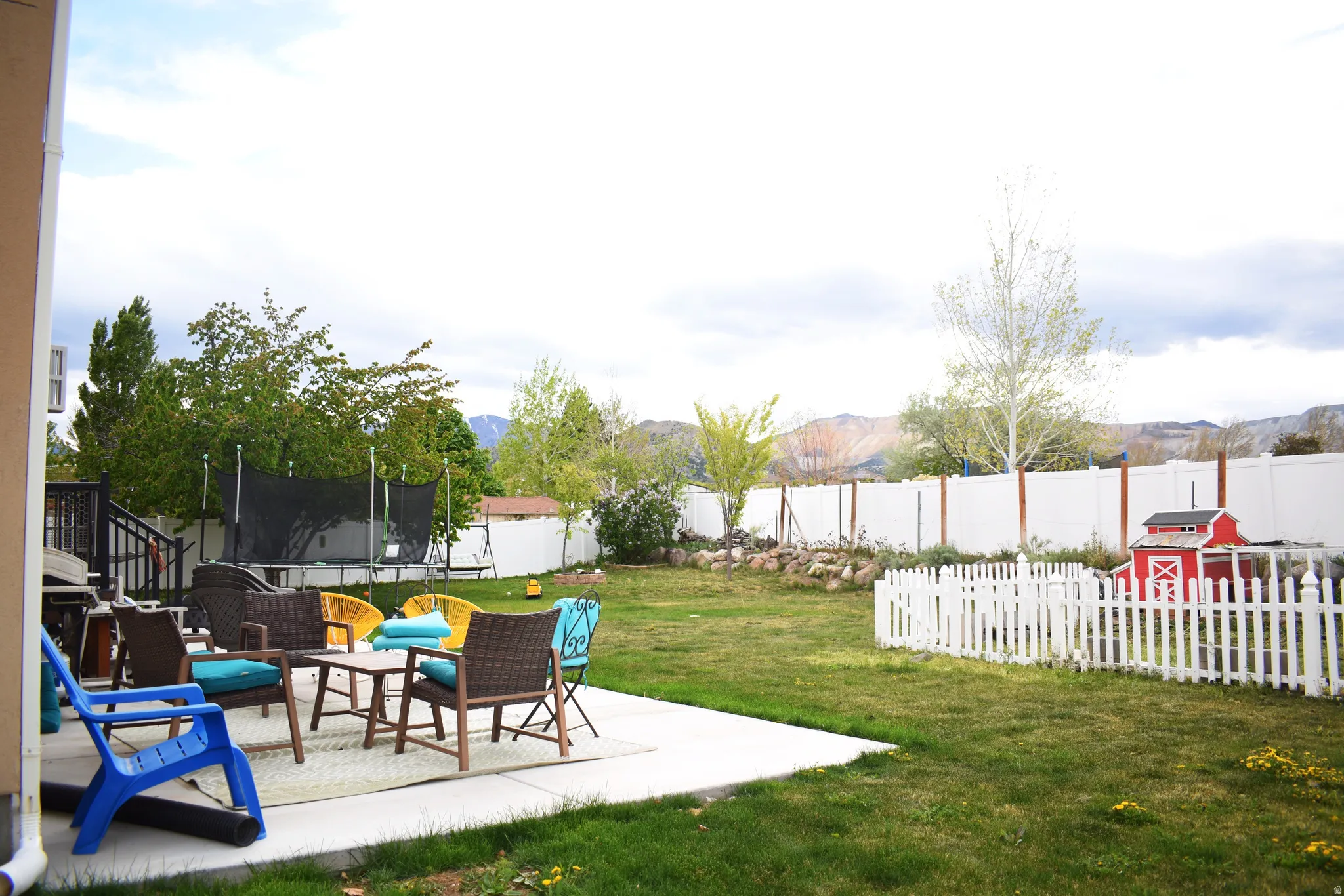 Fenced backyard featuring a trampoline, a patio area, outdoor lounge area, and a mountain view