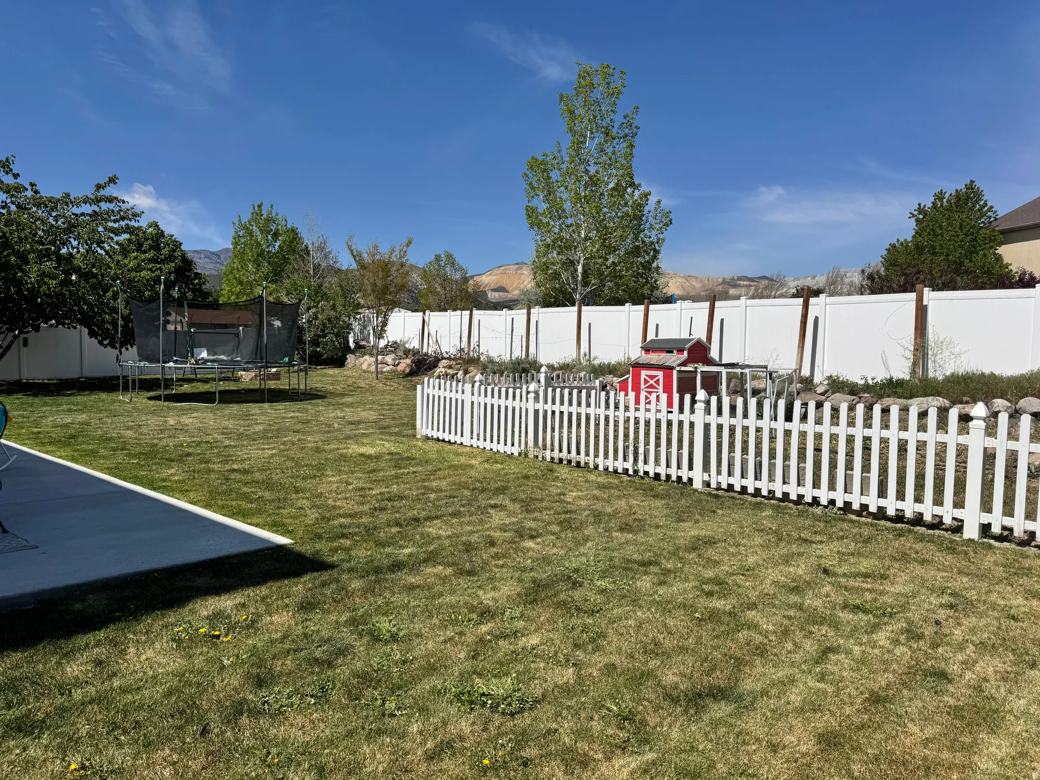 Fenced backyard featuring a trampoline